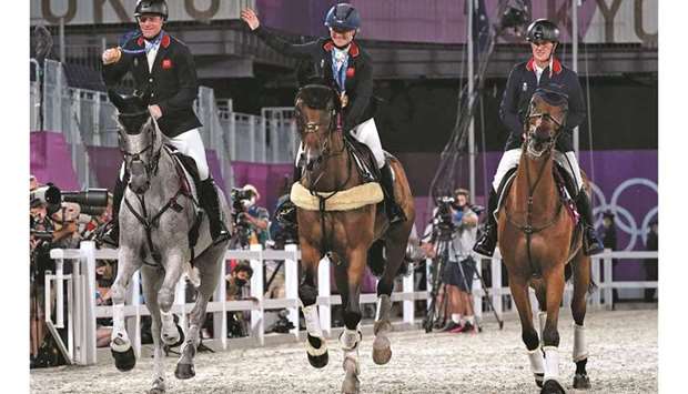 Britainu2019s team Tom McEwen, Laura Collett and Oliver Townend display their gold medals as they ride in the ring after winning the the equestrian eventing jumping teams final during the Tokyo 2020 Olympic Games at the Equestrian Park in Tokyo yesterday. (AFP)