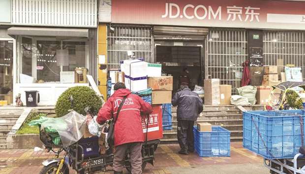 A delivery driver sorts parcels outside a JD.com warehouse in Shanghai. JD.comu2019s shares soared as much as 10.5% after the e-commerce giant reported revenue that beat estimates, defying a crackdown on the Chinese Internet sector that has depressed growth across the industry.