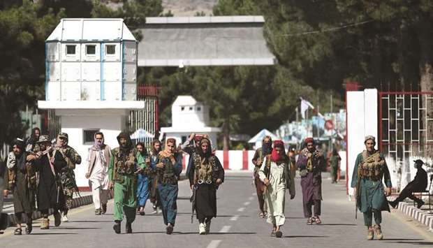 Taliban fighters walk at the main entrance gate of the airport in Kabul yesterday. (AFP)