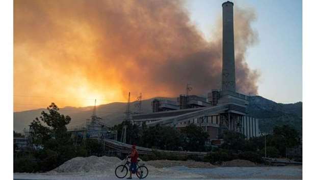A man pushes a bike along a road in the vicinity of a forest fire close to the Kemerkoy Thermal Power Plant in northen Turkey. (AFP)