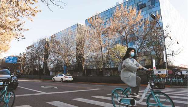 A woman rides a bicycle past the headquarters of Didi Chuxing in Beijing. Didi Global is weighing giving up control of its most valuable data as part of efforts to resolve a Chinese regulatory probe into the aftermath of its controversial US initial public offering, people familiar with the matter said.