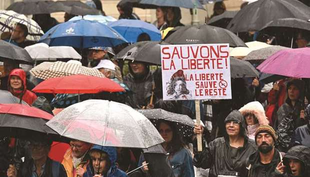 Demonstrators hold up banners and placards, one of which reads as u201cLetu2019s save freedom, freedom save the restu201d, during a national day of protest against the compulsory vaccination for certain workers and the mandatory use of the health pass called for by the French government in Nantes, western France, yesterday. (AFP)