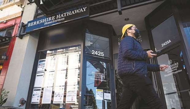A pedestrian wearing a protective mask walks past a Berkshire Hathaway HomeServices real estate office in San Francisco. The conglomerateu2019s collection of manufacturers and retailers bounced back during the second quarter after being hit hard as the pandemic ripped through the US last year.