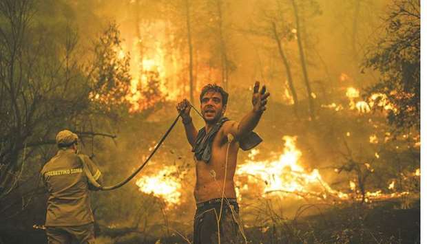 A local resident gestures as he holds an empty water hose during an attempt to extinguish forest fires approaching the village of Pefki on Evia (Euboea) island, Greeceu2019s second largest, yesterday. (AFP)