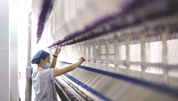 A worker stands in front of a machine on a yarn production line at the Fujian Strait Textile Technology factory in Putian. Chinau2019s economic risks are building in the second half of the year, with growth set to slow while inflation pressures are picking up, clouding the outlook for central bank support.