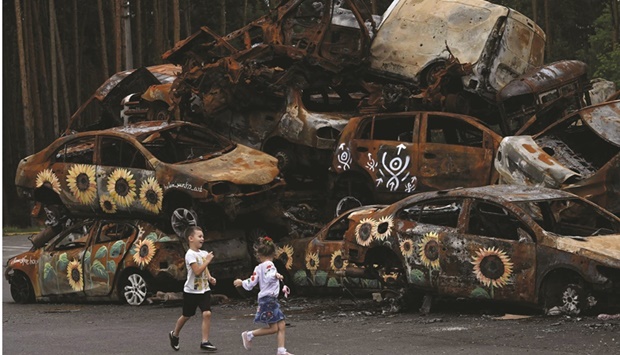 Children play at the symbolic cemetery of cars shot by Russian troops, some painted by local artists, in Irpin, Ukraine.