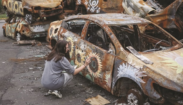 Ukrainian artist Olena Yanko paints a car destroyed during Russiau2019s attack on Ukraine and then collected from different places in the town of Irpin in Kyiv region, yesterday. (Reuters)