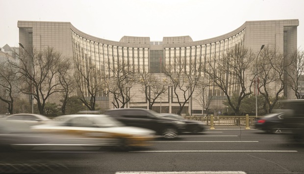 Vehicles travel past the Peopleu2019s Bank of China building in Beijing. Eight out of 12 economists and analysts polled by Bloomberg are forecasting that the PBoC will withdraw cash through MLF for the first time this year by offering less cash than the $89bn maturing this month.