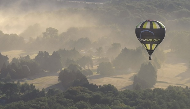 Dust from a quarry is seen behind a balloon flying at the annual Bristol International Balloon Fiesta, Britain, yesterday.