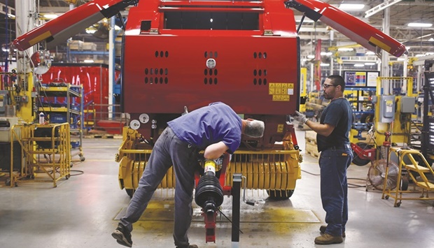 Workers review an assembled New Holland round baler at the companyu2019s Haytools factory in Pennsylvania (file). As US industrial production rose to an all-time high last month despite the high interest rate environment, the Federal Reserve is expected to stay on its aggressive monetary policy tightening path.