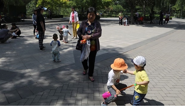 Children play next to adults at a park in Beijing, China June 1, 2021.