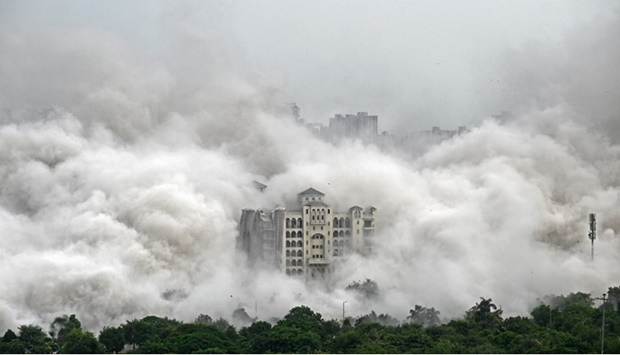 A residential building is engulfed in dust after a controlled implosion demolished the 100-metre-high residential ,Twin Towers, in Noida on the outskirts of New Delhi, on August 28, 2022.