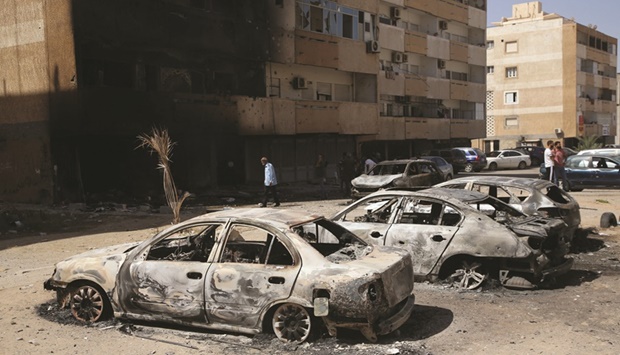 People gather next to burnt cars after Saturdayu2019s clashes in Tripoli, Libya.
