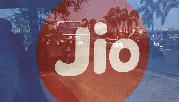 Commuters are reflected on an advertisement of Reliance Industriesu2019 Jio telecoms unit at a bus stop in Mumbai (file). Earlier this month, Jio swept up more than a third of the available spectrum in Indiau2019s first-ever 5G airwave auction, bidding 881bn rupees ($11bn).