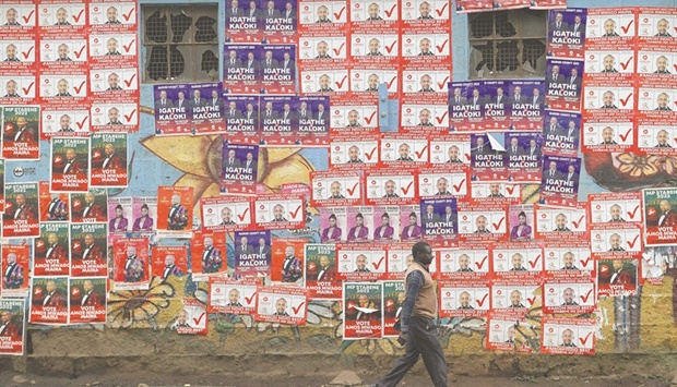 A man walks past campaign posters of various candidates pasted on walls in Nairobi, ahead of Kenyau2019s general election this month.