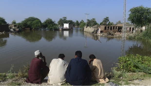 Flood affected people sit in higher ground near their flooded homes in Shikarpur, Sindh province, on August 31, 2022.
