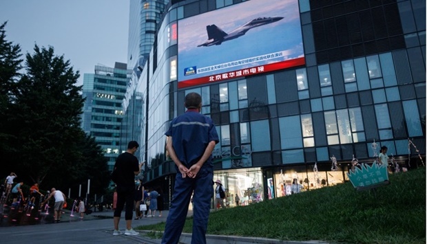 A man watches a CCTV news broadcast, showing a fighter jet during joint military operations near Taiwan by the Chinese People's Liberation Army's (PLA) Eastern Theatre Command, at a shopping center in Beijing, China. REUTERS