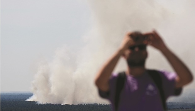 A man takes pictures as smoke billows over Grunewald forest in Berlin.