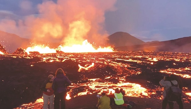 People are seen taking photos as Fagradalsfjall volcano erupts near Reykjavik, in this screen grab obtained from a social media video.