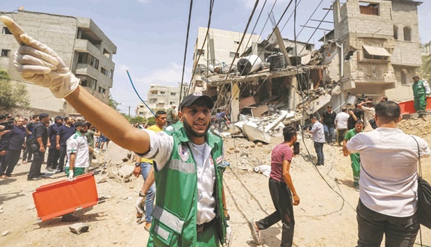 A paramedic cautions people at the scene of an Israeli air strike in Gaza City.
