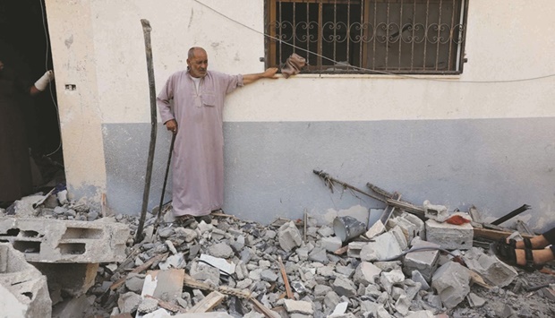 A Palestinian man stands near the rubble of a house destroyed in an Israeli air strike.