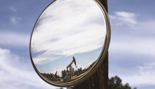 An oil pumpjack is reflected in a mirror as it operates near Ventura, California. The Inflation Reduction Act of 2022 holds provisions for climate change, including tax incentives for clean energy production, in what would be a major legislative accomplishment for the Biden administration.