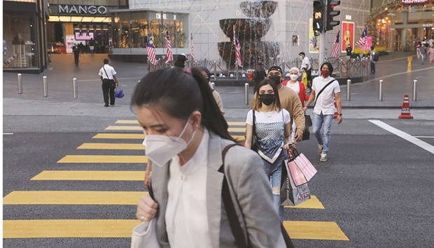 People wearing protective masks cross a street outside a shopping mall in Kuala Lumpur (file). Malaysiau2019s gross domestic product grew 5% in three months to March and its unemployment rate has been on a declining trend for over a year.