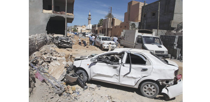 Damaged cars and debris are seen at the site of a bombing that targeted the house of former security chief Hashem Besher in Tripoli yesterday.