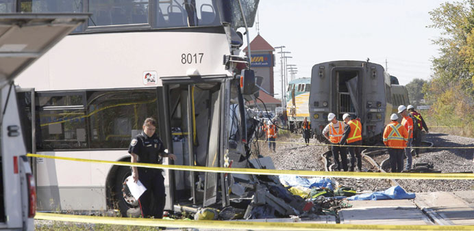 Investigators examine the scene of an accident involving a bus and a train in Ottawa yesterday.  The crash left six people dead.