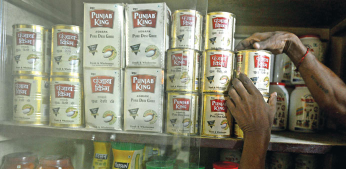 An Indian shopkeeper stacks packets of ghee in his shop in Siliguri. India is desperately trying to wean consumers off the much-loved spicy, rich dish