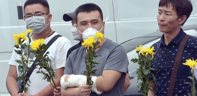 This picture taken on Tuesday shows an injured man holding flowers during a vigil for firefighters and soldiers killed during the explosions in Tianji