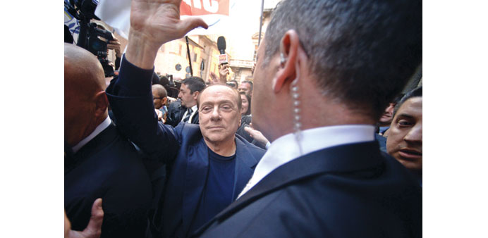 Berlusconi, surrounded by bodyguards, waves at his supporters as he arrives at his home in downtown Rome.