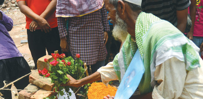 A family member of a missing garment worker pays tribute to the victims at the site of the April 24 nine-storey building collapse in Savar, on the out