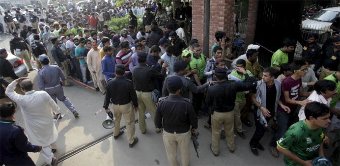 Policemen assist people lining up to enter the Gaddafi Stadium to watch the first Twenty20 Cricket match 