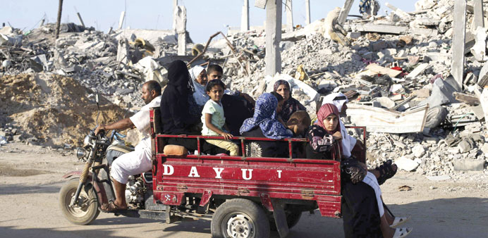 Palestinians flee their homes in a motorcycle rickshaw past a destroyed house in the east of Khan Younis in the southern Gaza Strip yesterday.
