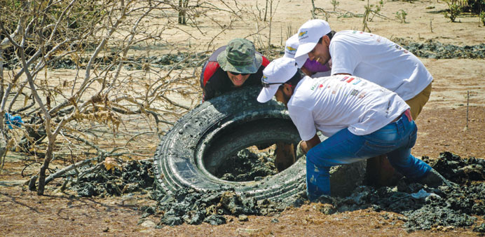 Volunteers pull a big tyre from the mud. PICTURE: iloveqatar.net.