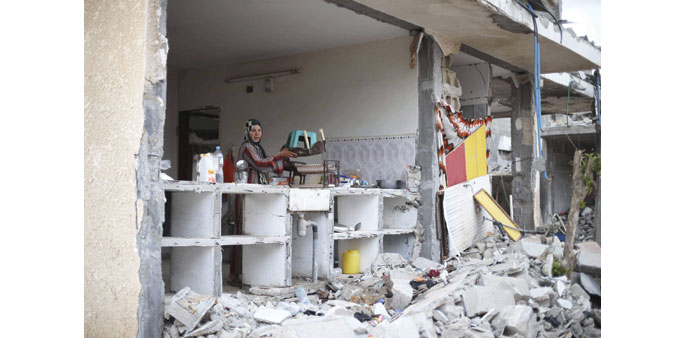 A Palestinian woman removing belongings from her house which was damaged during the Israeli offensive, on the fifth day of ceasefire in Khan Younis in