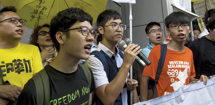 Students leaders Nathan Law (left), Alex Chow and Joshua Wong (right) chant slogans as they arrive at police headquarters in Hong Kong yesterday.