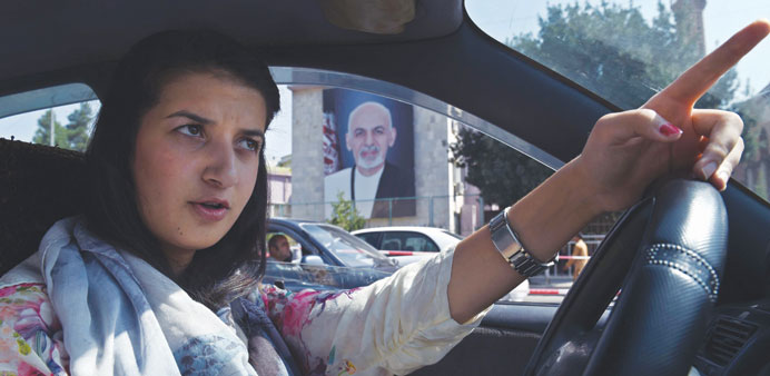 Afghan woman, Rokhsar Azamee, 23, gestures as she drives her car along the streets of Kabul. 