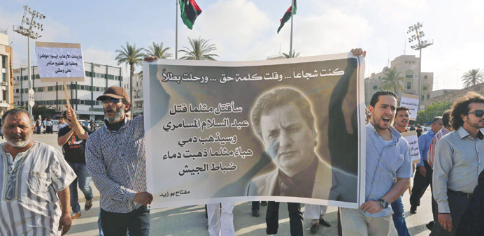 Protesters hold a banner bearing a portrait of Meftah Bouzid, editor of the weekly newspaper Burniq, during a rally to protest against his assassinati