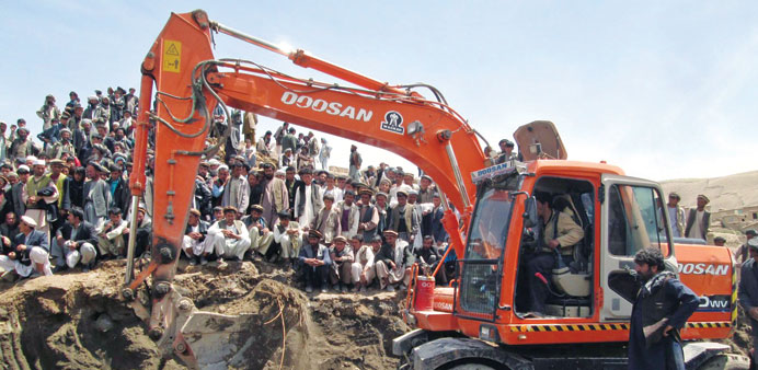 Afghan villagers affected by landslide wait as a crane removes debris during a search of bodies of the victims, in Argu village, Badakhshan province, 