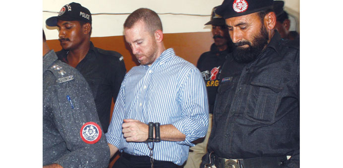 In this photograph taken on May 6, 2014 Pakistani policemen escort an alleged US FBI agent under arrest as they leave the local court in Karachi.
