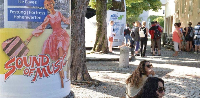 Tourist sitting next to an advertising column advertising a Sound of Music tour at the Mirabell Place in Salzburg.