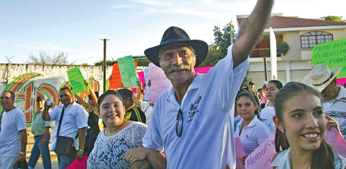 Jose Manuel Mireles, a leader of the Self-Protection Police, waves during a march.