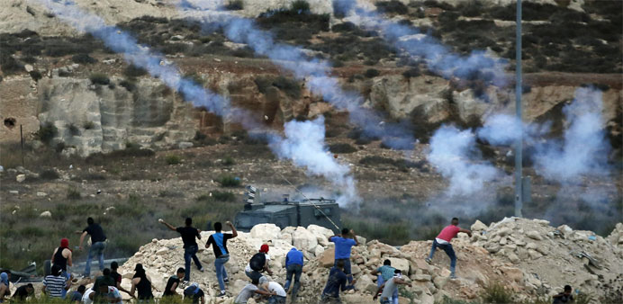 Israeli security forces fire tear gas towards Palestinian students throwing stones during clashes 