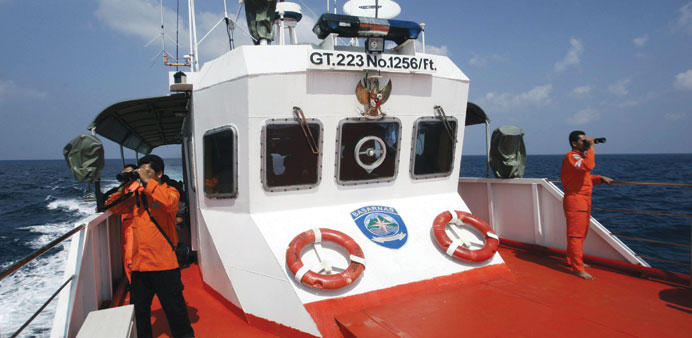 Rescue members use binoculars to look for the missing Malaysia Airlines flight MH370, that disappeared from radar screens in the early hours of Saturd