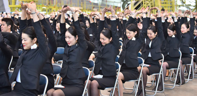 New employees of Japan Airlines Group stretch prior to their entrance ceremony at a hangar in Tokyo.
