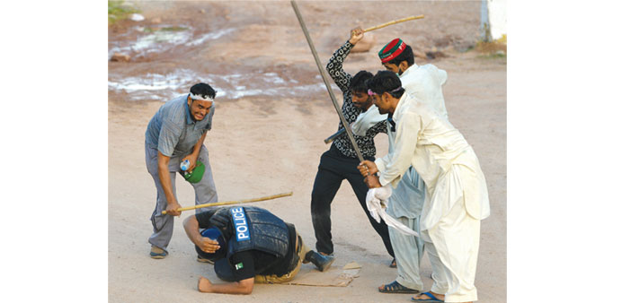 Anti-government protesters beat a riot policeman during a protest in Islamabad yesterday.