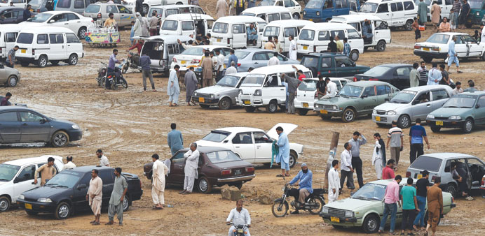 Pakistanis gather around cars at the Sunday car market in Karachi.