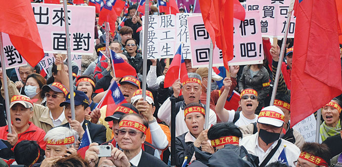 People wave national flags and placards as they demonstrate to support the government and a controversial Taiwan-China trade pact in Taipei yesterday.